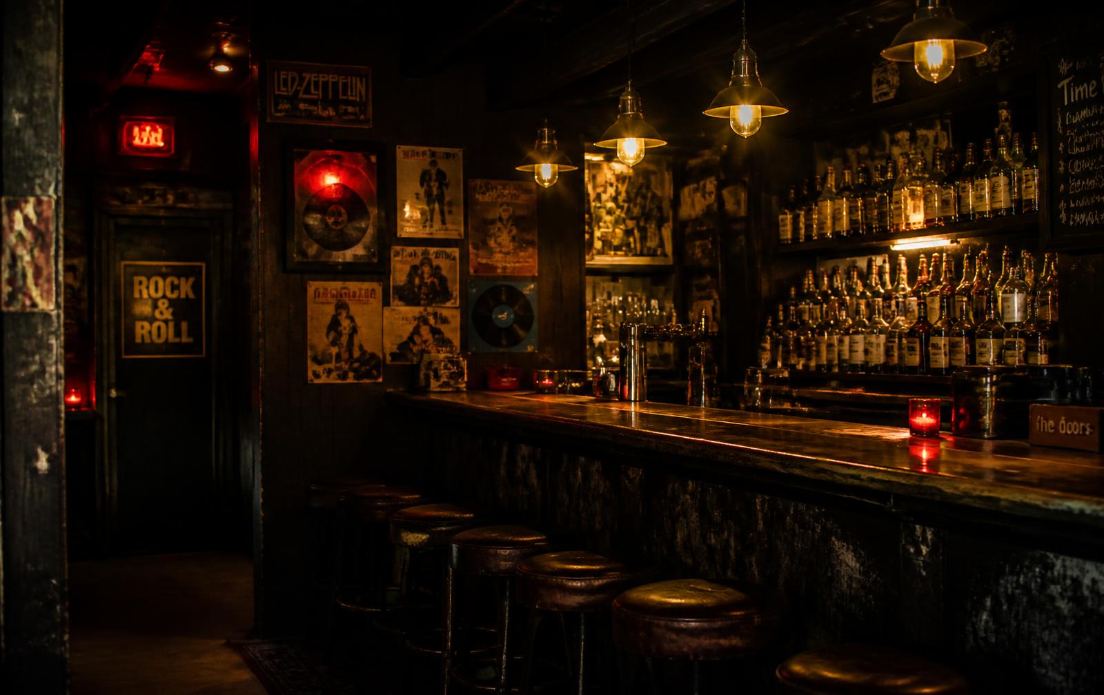Interior do Sebo Bar: balcão de madeira envelhecida, discos e lâmpadas âmbar em luz baixa
